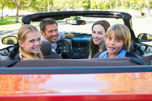 Family in convertible car smiling